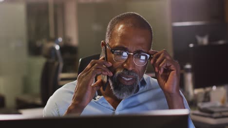 professional businessman removing his glasses while talking on his phone in modern office in slow mo