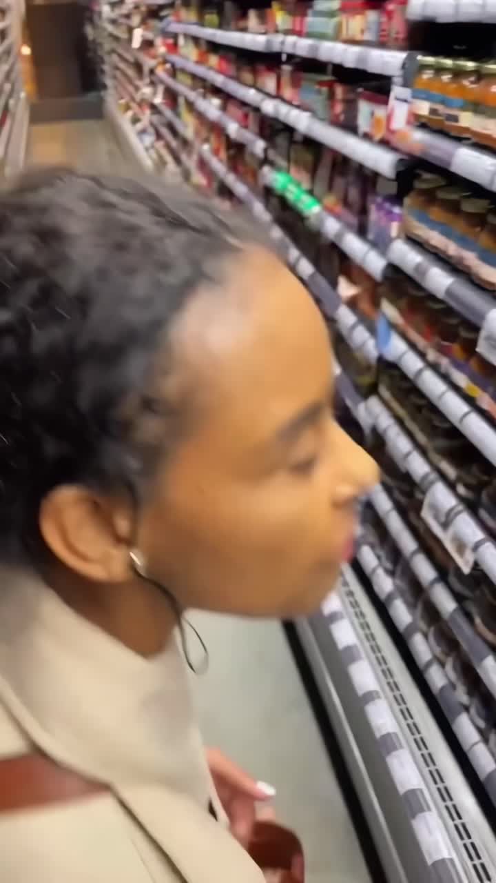Video captures a woman shopping in a grocery aisle, viewed from behind at eye level