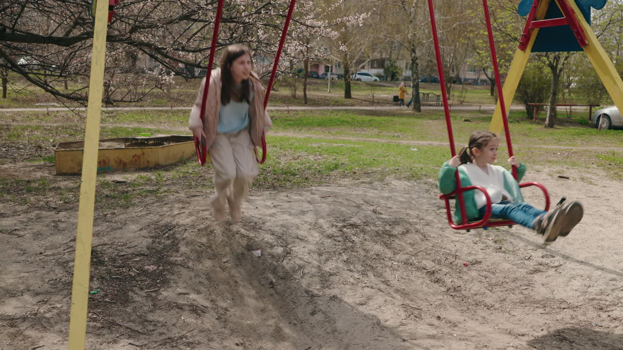 Children Swinging on a Playground in a Park