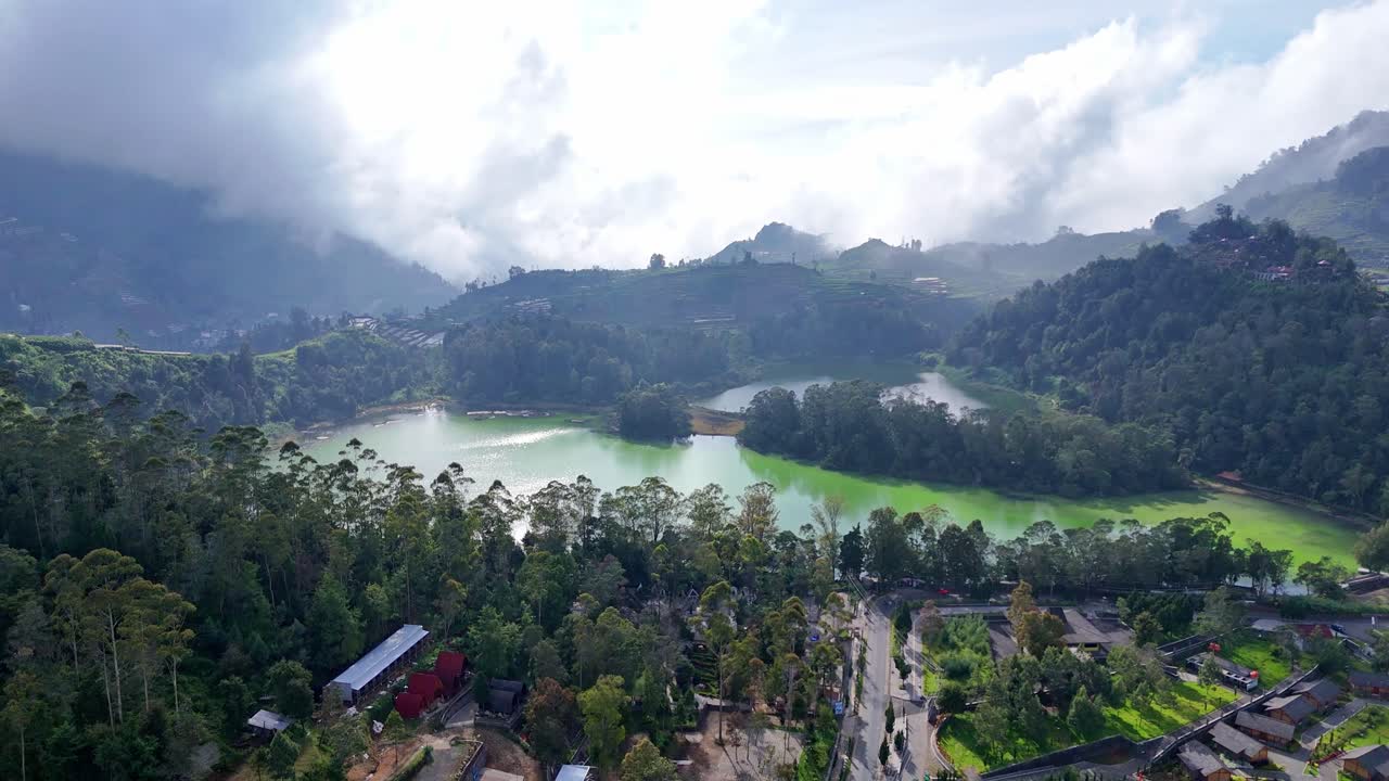 Drone footage showcasing a crater lake with vivid green and blue tones, nestled among lush mountain forests. Peaceful and breathtaking scenery in a tropical highland environment
