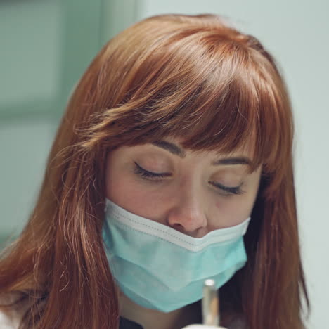pretty woman dentist in a mask is conducting a dental procedure and talking with a client on the background of the office. blurred background. close-up.