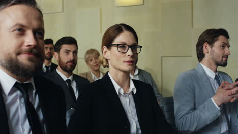 close-up view of caucasian businessman and businesswoman sitting among the audience and listening to the speaker at a conference