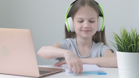 happy school girl wearing wireless headphones studying online at virtual class with teacher tutor