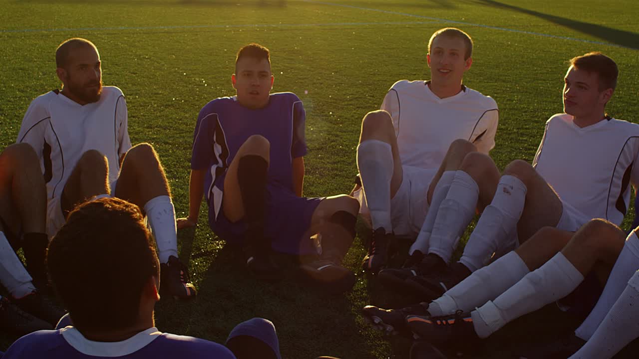 한 축구팀이 서클에 앉아 해가 지는 동안 재미있는 게임을 하고 있다.