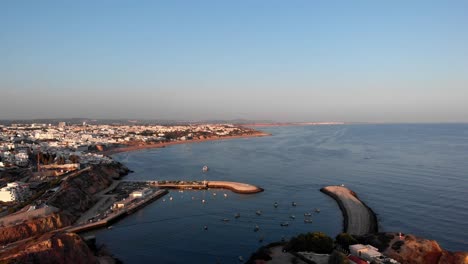 4K-Aerial-view-of-city-with-small-harbor-during-sunset-in-Albufeira,-Portugal