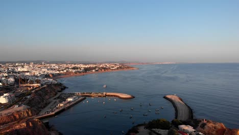 4k aerial view of city with small harbor during sunset in albufeira, portugal