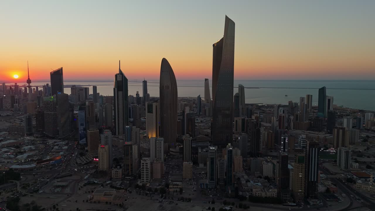 Breathtaking 4K drone shot of Kuwait City at sunrise. Towers glow under golden skies with the calm Gulf in the background. Ideal for cinematic, travel, or architectural footage.