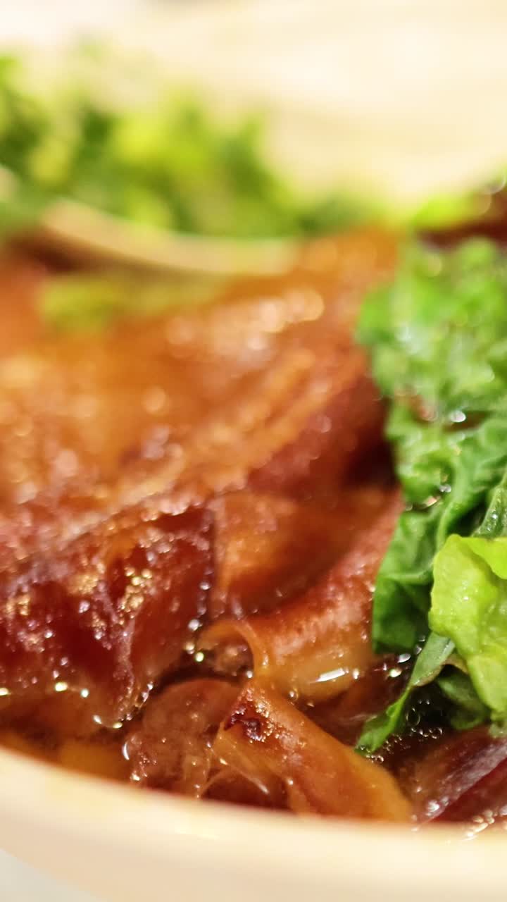 Chopsticks lifting beef from noodle soup