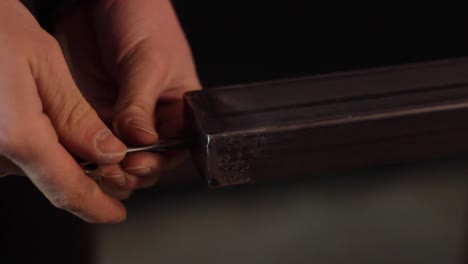 closeup of hands creating threads in metal frame using lathe chuck key