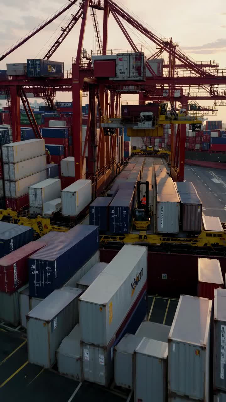 Riprese aeree di un vivace porto con container impilati e gru al tramonto