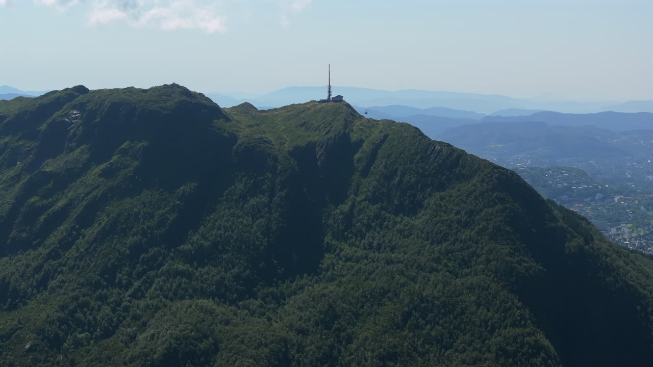 Drone gliding around the north side of Ulriken, following the cable car to the summit with panoramic mountain views