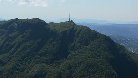 drone gliding around the north side of ulriken, following the cable car to the summit with panoramic mountain views