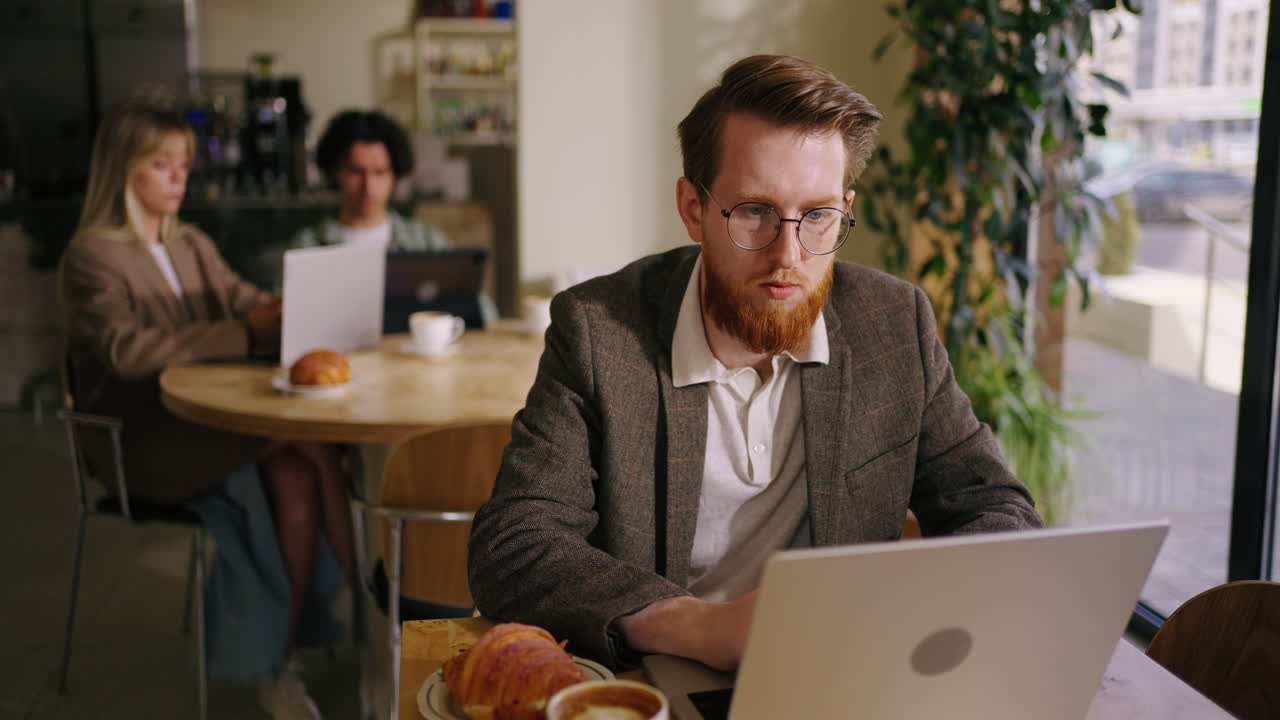 Uomo che lavora al portatile in un caffè