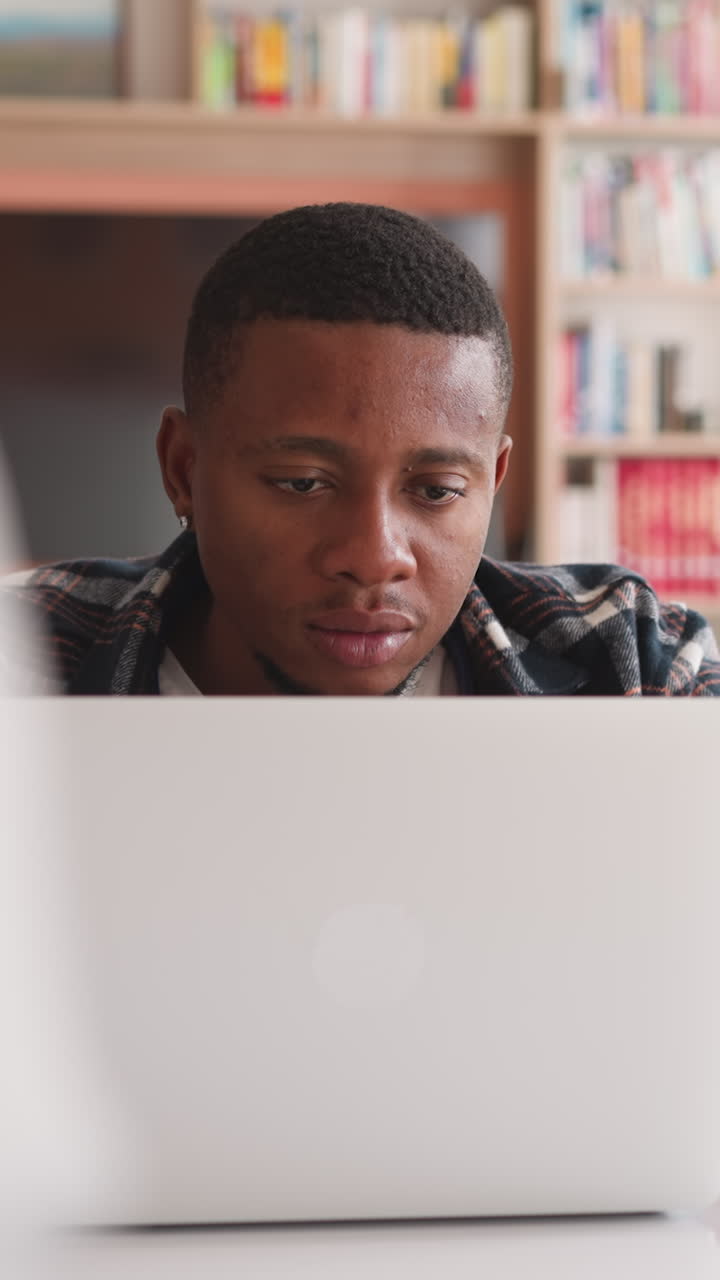 Guy with female group mates write research project using laptop. Students write researching in library using modern devices. Learning with modern technology