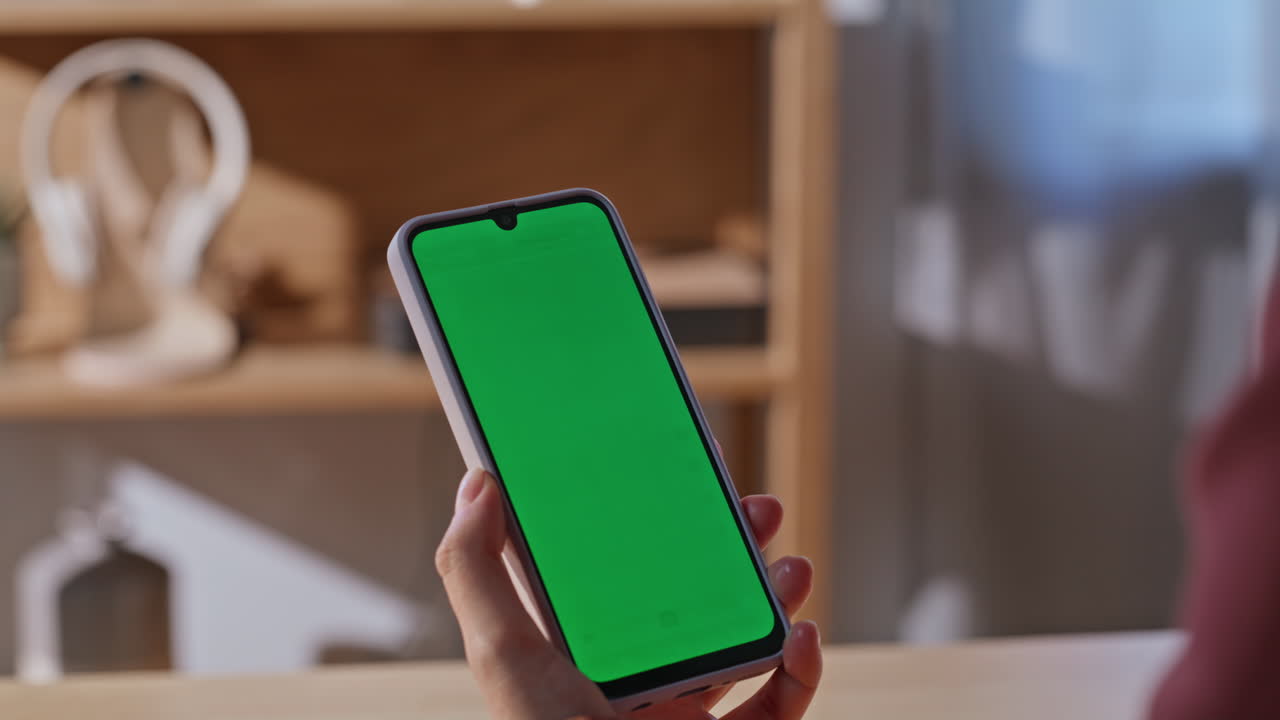 Housewife finger swiping greenscreen smartphone modern sunny apartment closeup