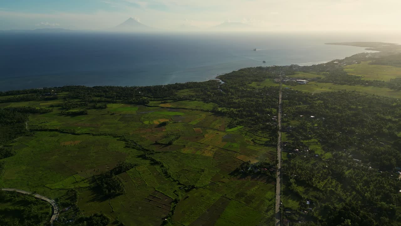 Aerial view of tropical island province vista with lush greenery, stunning coastline and Mayon Volcano in background - Catanduanes, Philippines