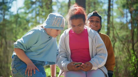 children looking at a smartphone in a forest