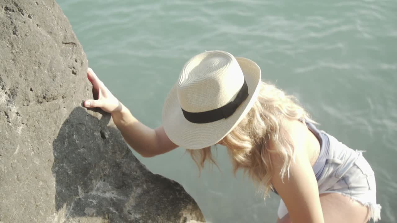 A Young Woman Climbing Up The Rocks Near The Shallow Sea Water During Summer In Ontario, Canada - Close Up Shot