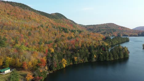 Frente-Al-Lago-Celestial-Y-Colorido-Paisaje-Otoñal-En-Una-Zona-Rural-De-Nueva-Inglaterra,-Vermont,-EE.UU.,-Vista-Aérea,-Bosque-Vívido-Y-Aguas-Tranquilas,-Tiro-Con-Drones