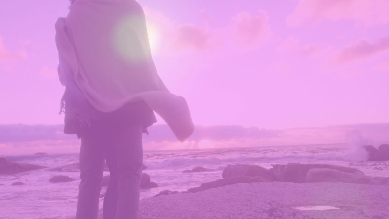 Couple walking along rocky shoreline at sunset, with floating finance graph animations