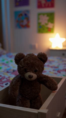 a teddy bear in a wooden box in a child's bedroom with a star night light