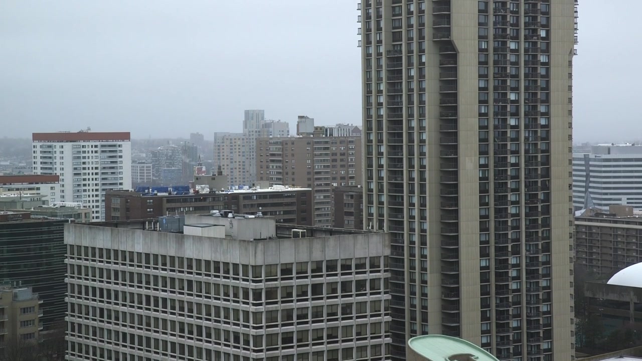Tomada em inclinação lenta para cima revelando um denso aglomerado de edifícios de apartamentos altos em Boston, Massachusetts, em um dia nublado