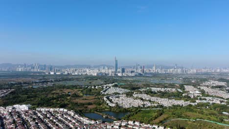 hong kong and shenzhen border line over hong kong rural houses with shenhzen skyline in the horizon, aerial view