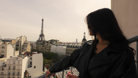 mujer de pie en el balcón, hotel, torre eiffel en el fondo, paralaje, retrato en primer plano, sobre el hombro