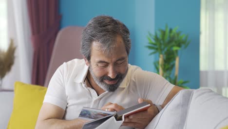 the man looking at his child's album cries with longing and his hand is shaking.