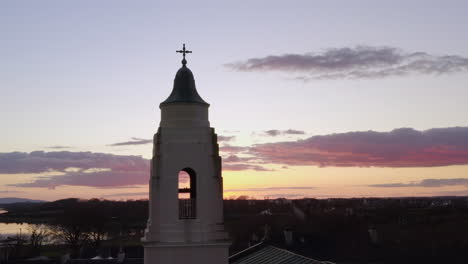medium aerial orbit of historic clarinbridge church framed by vibrant sunset sky and warm colors