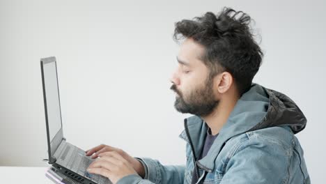 primer plano de un hombre indio del medio oriente trabajando en una computadora portátil, pareciendo decepcionado