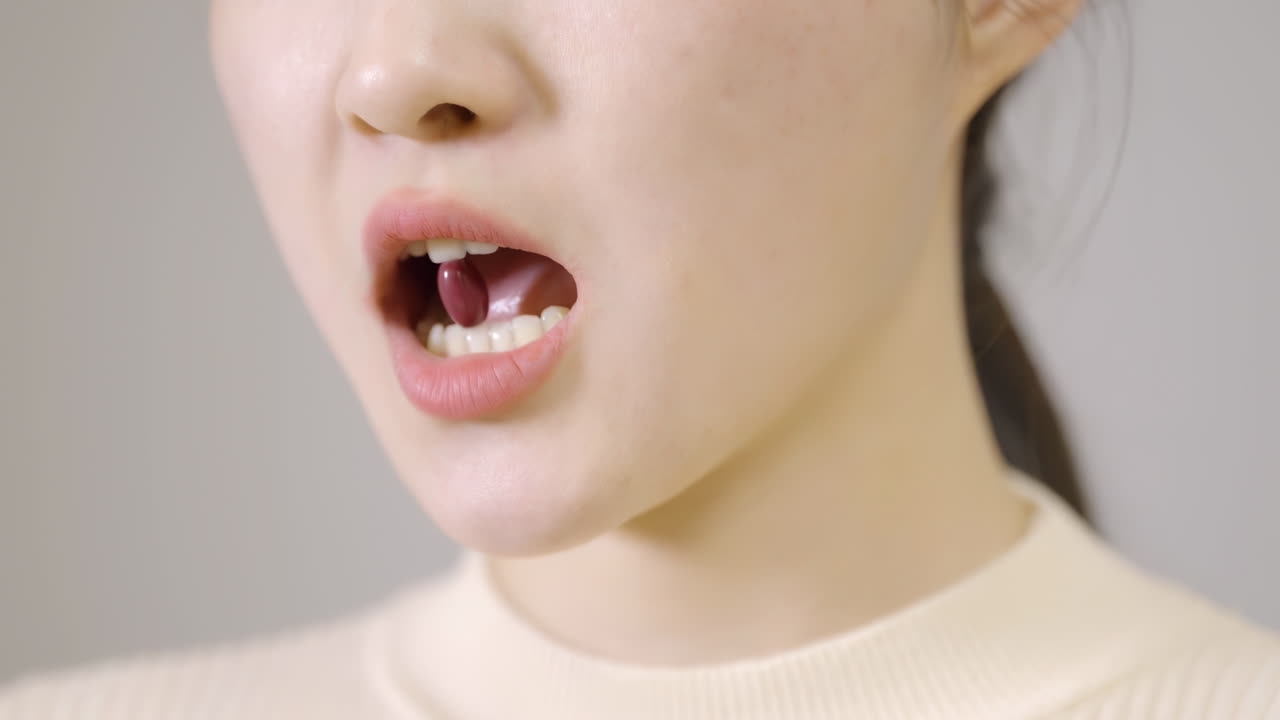 美しい若い女性が健康的なフィッシュオイルのソフトジェル栄養補助食品を口にしている。これは、減量ダイエットカプセル、または体の肌の健康維持、病気の緩和を目的とした薬のコンセプト。