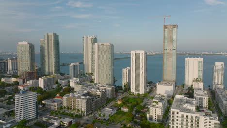 Los-Delanteros-Vuelan-Sobre-El-Barrio-Urbano.-Hilera-De-Modernos-Edificios-Residenciales-Altos-En-El-Paseo-Marítimo-Iluminados-Por-Un-Sol-Brillante.-Miami,-Estados-Unidos