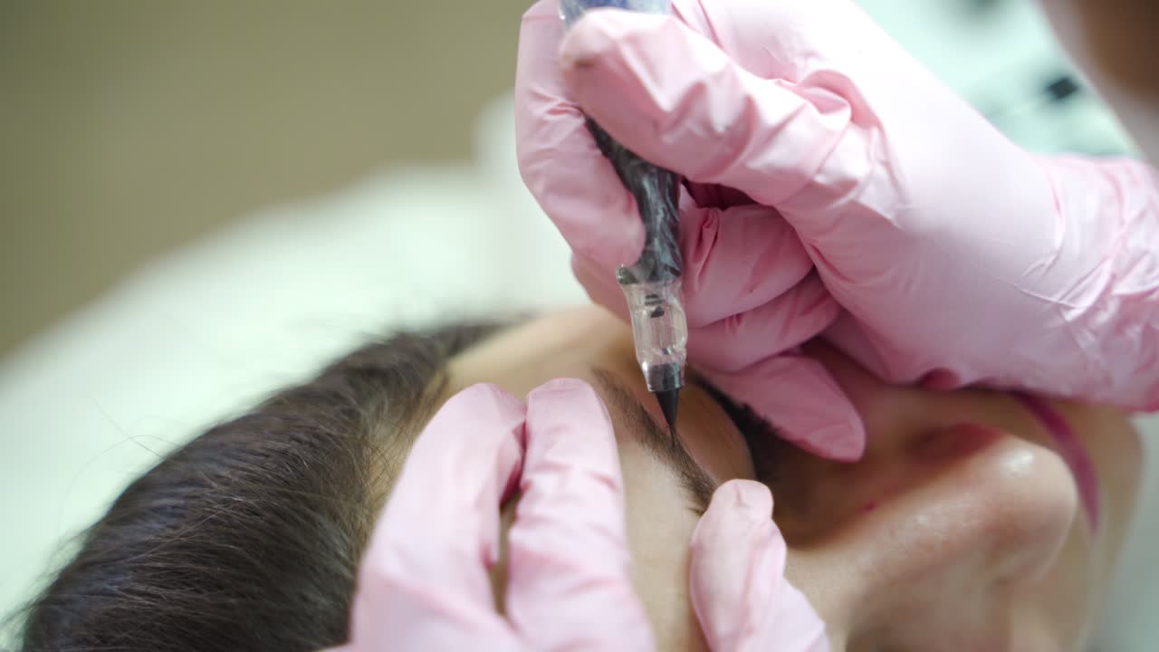 a cosmetologist is making eyebrow staining with a professional needle for permanent eyebrow makeup. Modern cosmetology methods