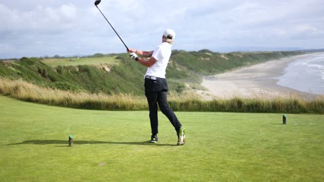 talented young golfer teeing off on tee box on coastline golf course