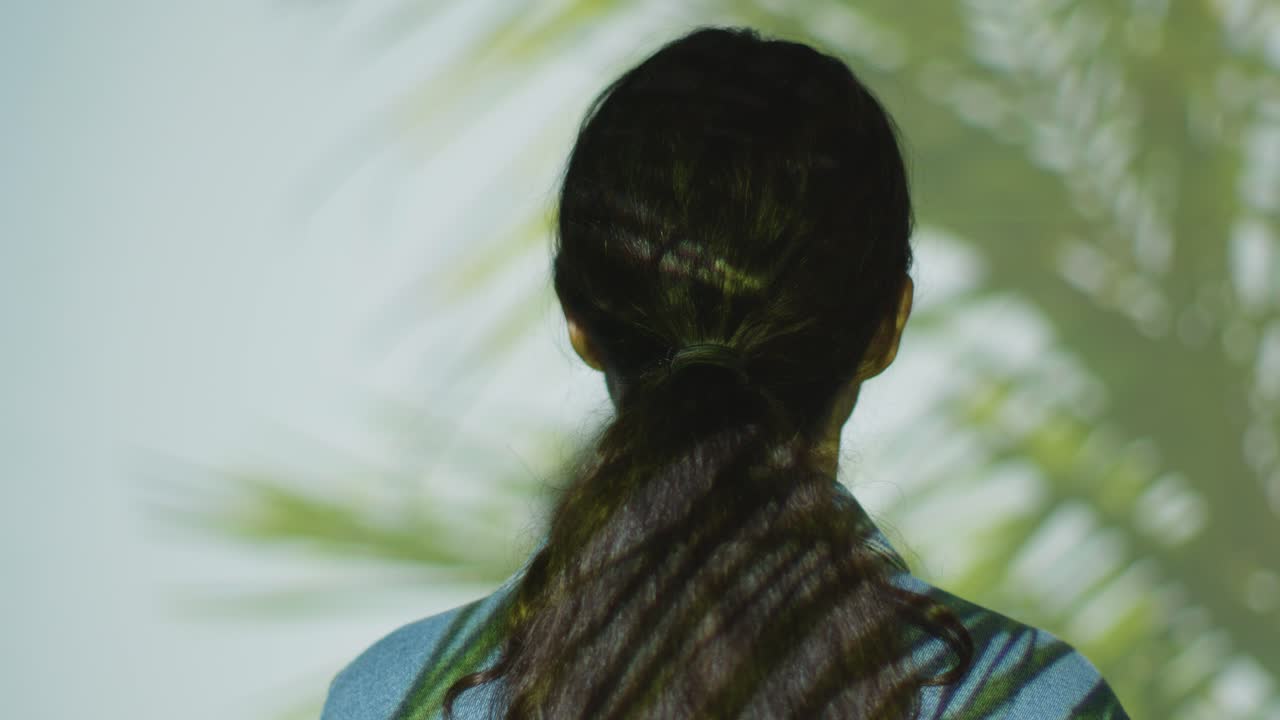 몰입 예술 전시회를 방문하는 여성은 그녀의 몸에 투사되는 종려나무 잎의 이미지와 상호 작용합니다.