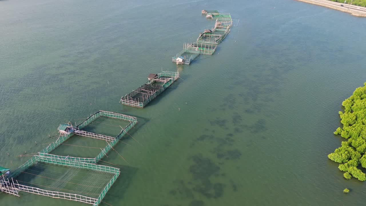 High drone view of floating fish pens arranged in a geometric pattern on calm green waters in the Philippines. Ideal for topics on aquaculture, fishing, and sustainable seafood