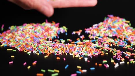 hands releasing rainbow sprinkles onto a surface