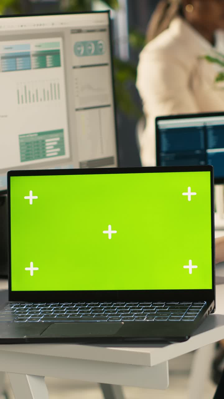 Vertical video Green screen laptop on office desk next to employee editing documents