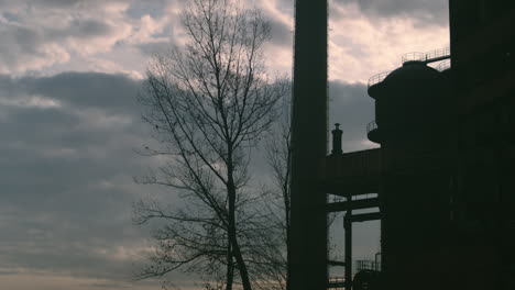 moody timelapse of factory blast furnace silhouetted by evening clouds