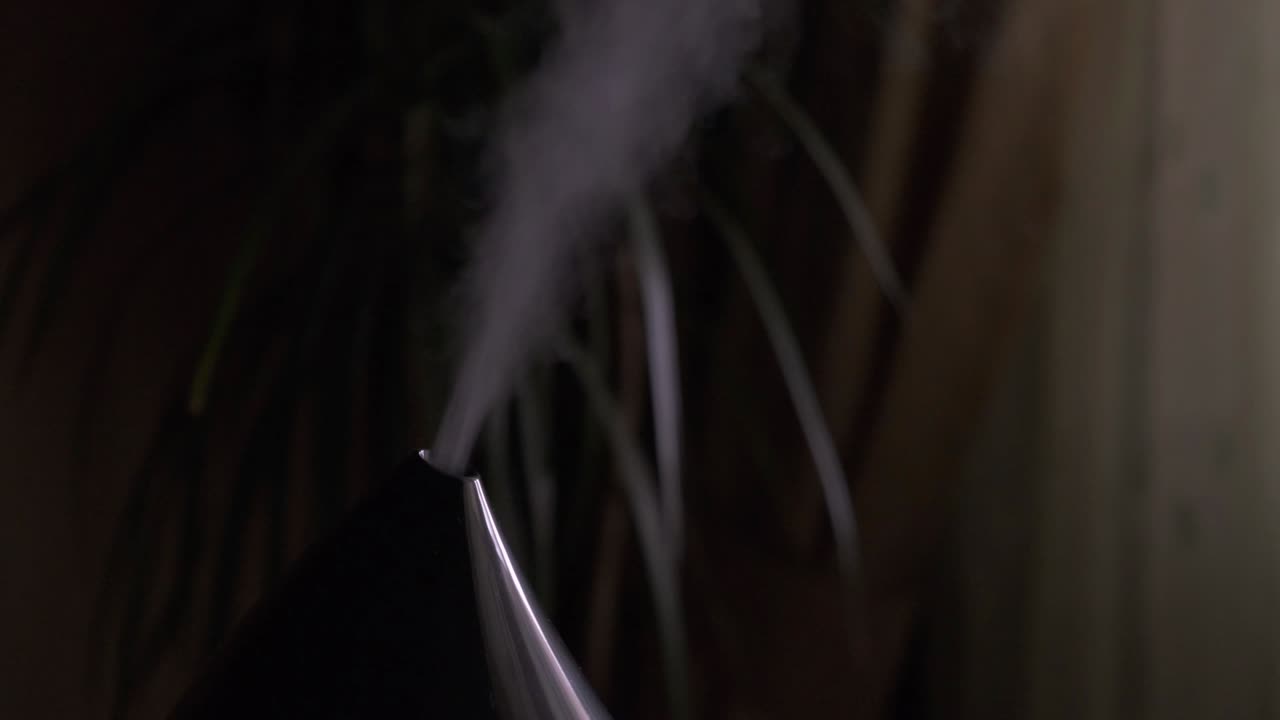 vapor de un humidificador de aire moderno en una habitación oscura.