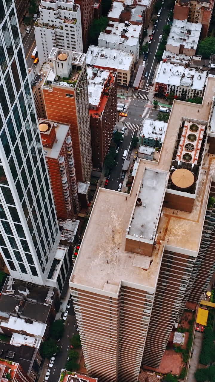 Descending over the tops of skyscrapers in New York. Marvelous metropolis with lively traffic on roads. Vertical video