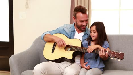 happy father and daughter playing guitar