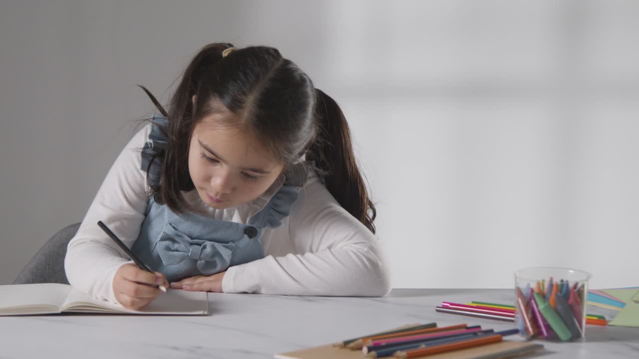 foto de estudio de una joven en la mesa escribiendo en un libro escolar