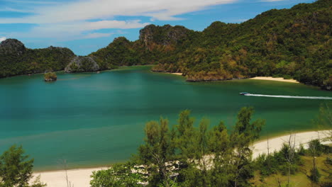 Traditional-Malaysian-boat-sailing-between-the-Tanjung-Rhu-Beach-and-two-small-islands-nearby,-Pulau-Gua-and-Pulau-Bebilis