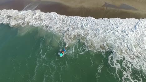 Top-down-aerial-view-of-a-fit-man-running-into-the-ocean-with-a-surf-board