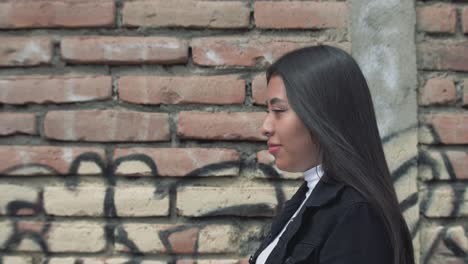 Close-up-of-a-hispanic-walking-along-red-brick-walls-with-graffiti-in-the-city