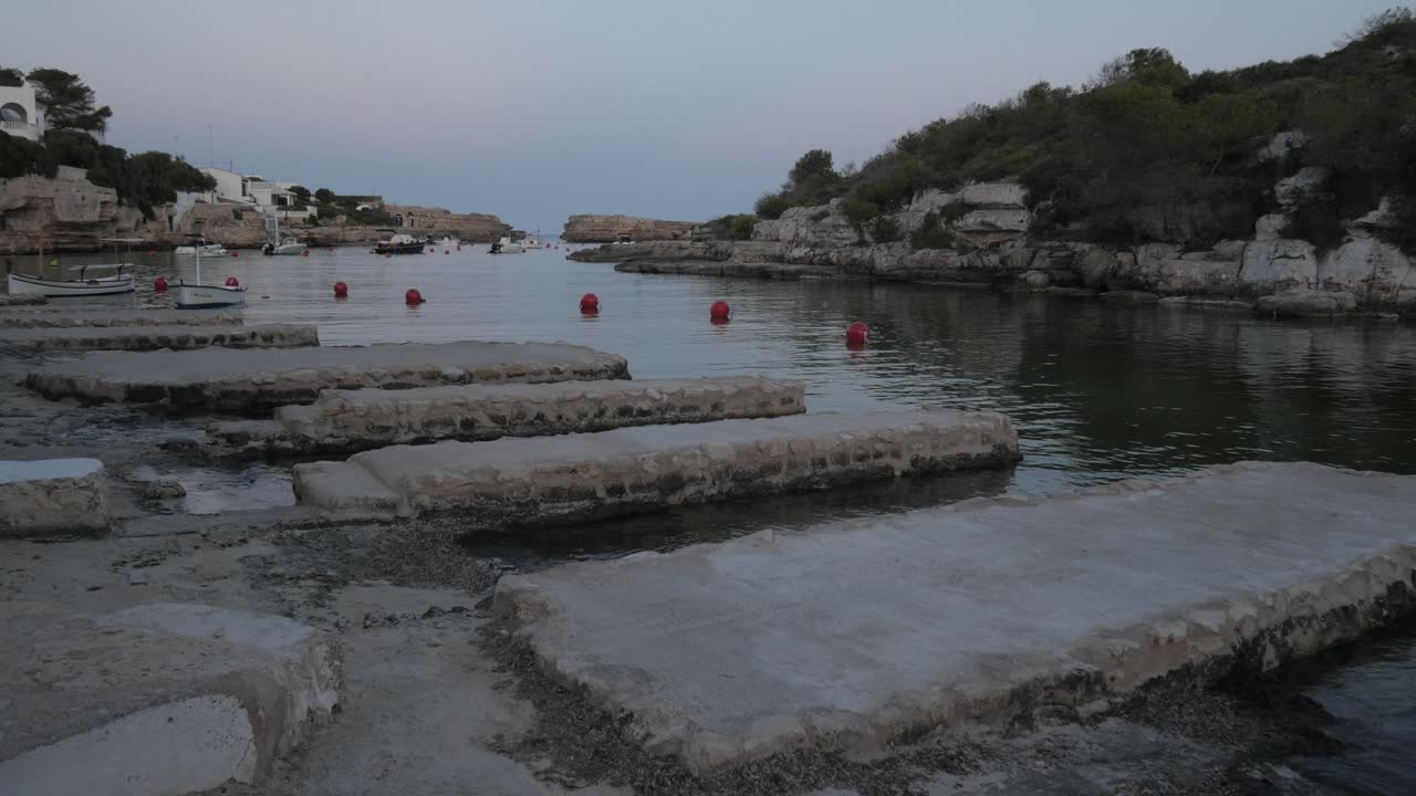 Cala Alcaufar with its tranquil waters and rocky formations in the early evening