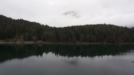 boat house on the shore of a perfect alpine lake, blindsee with low clouds partly revealing a mountain behind