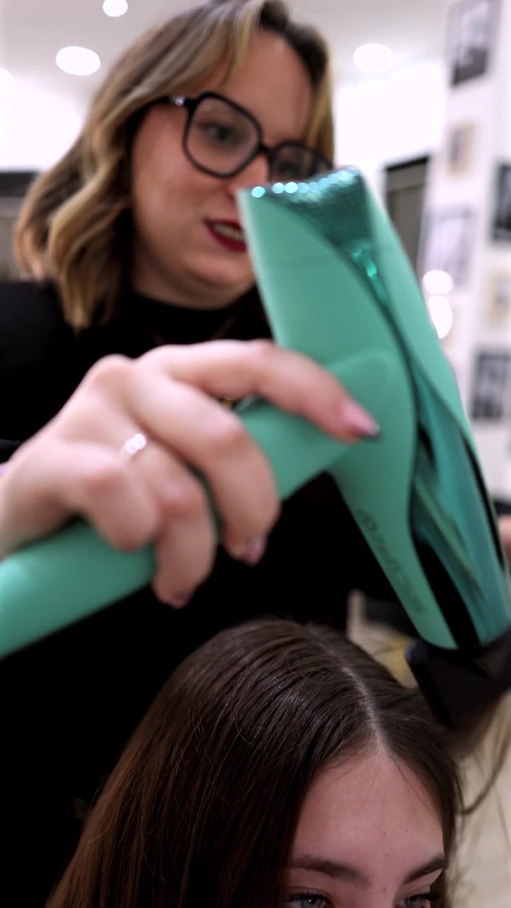 Professional Hairdresser Blow Drying Client's Hair in Salon